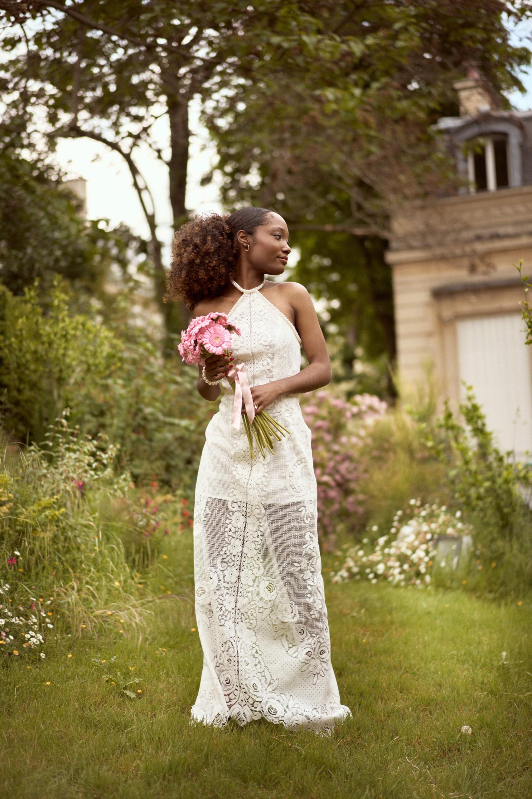 Sarah portant sa robe en dentelle dans un jardin fleuri
